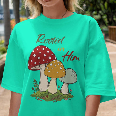 Person wearing a green t-shirt with mushroom design and 'Rooted in Him' text.