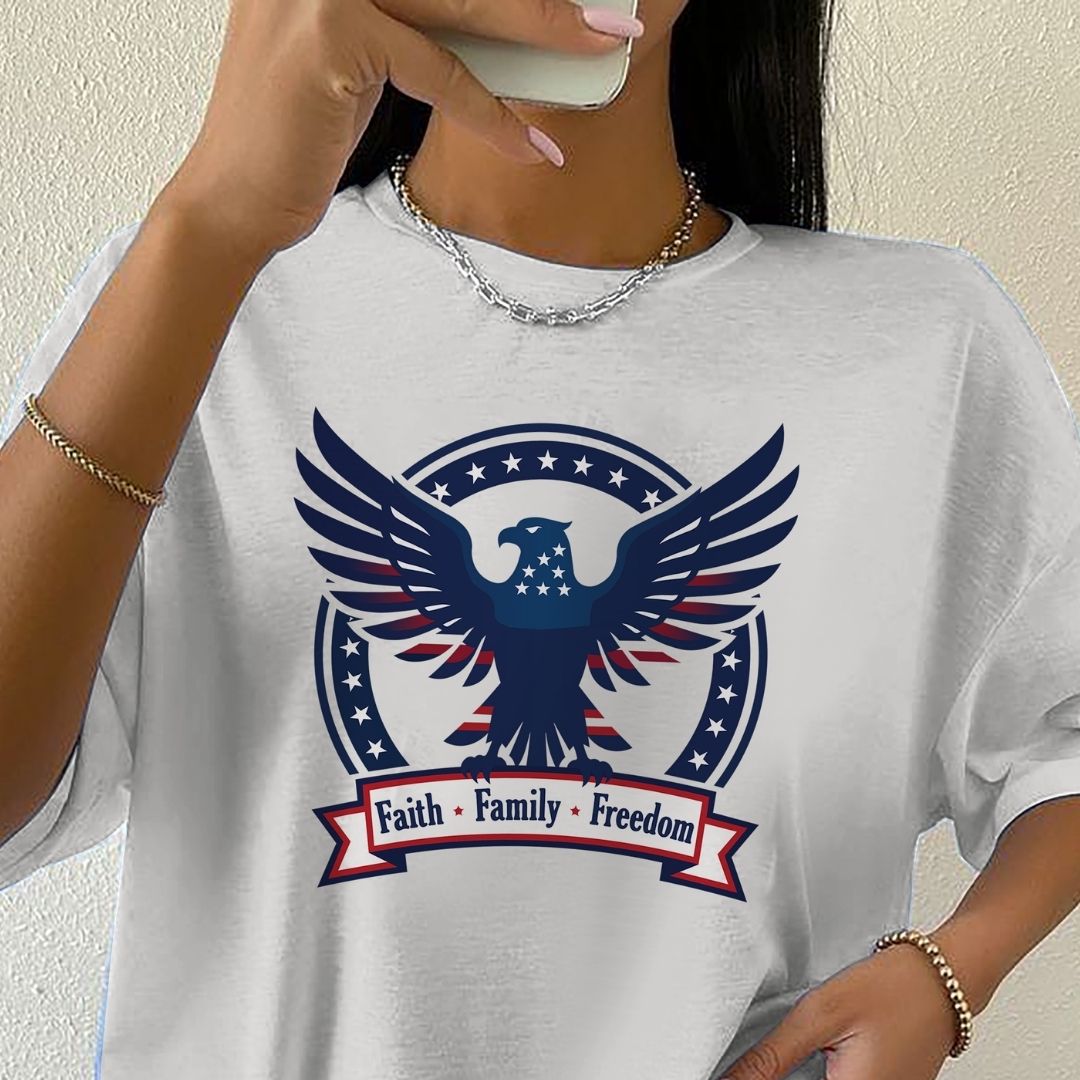 Person wearing a white t-shirt with an eagle design and 'Faith Family Freedom' text.