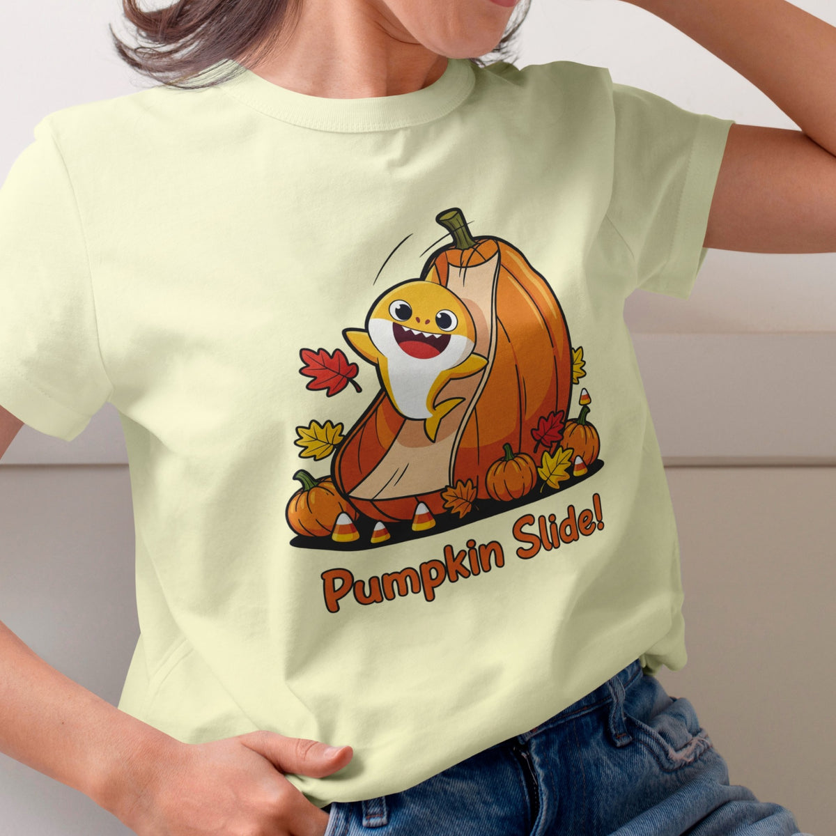Person wearing a light green t-shirt with a cartoon character and 'Pumpkin Slide!' text, standing against a neutral background.