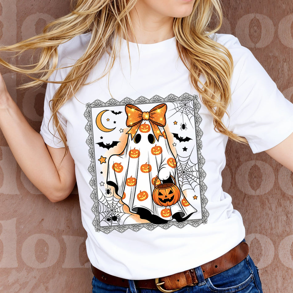 Person wearing a white t-shirt with a Halloween-themed design featuring pumpkins and a bow.