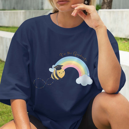 Person wearing a navy blue t-shirt with a colorful graphic of a bee, rainbow, and graduation cap.