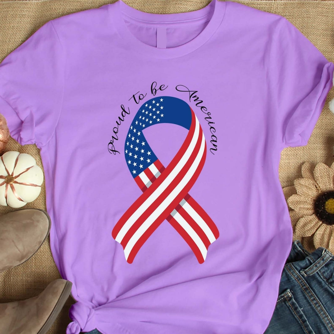 Purple t-shirt with American flag ribbon design and 'Proud to be American' text on a textured surface.