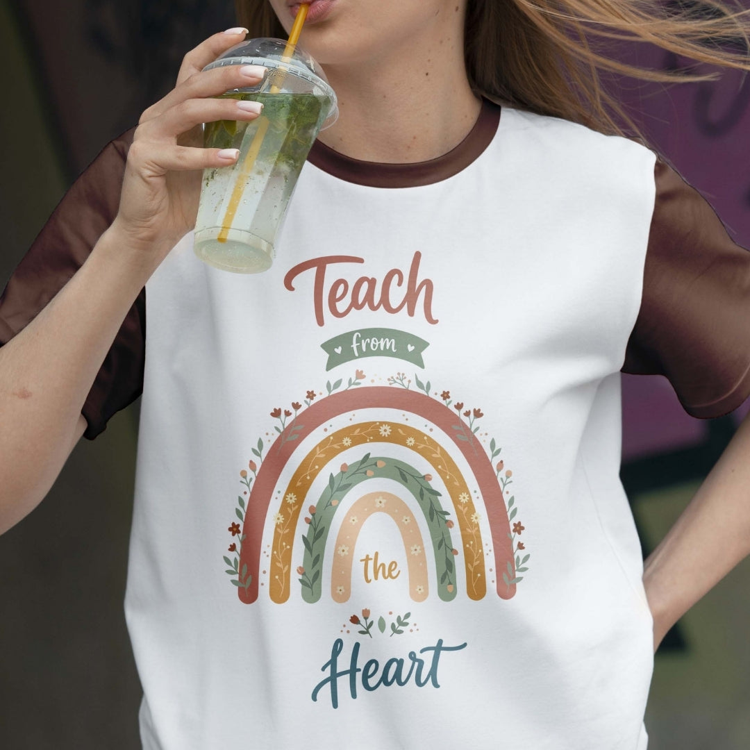 Person wearing a white t-shirt with a rainbow design and text, holding a drink.