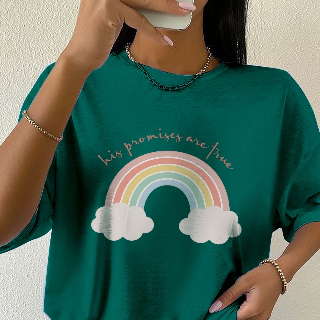 Person wearing a green t-shirt with a rainbow and cloud design and text.