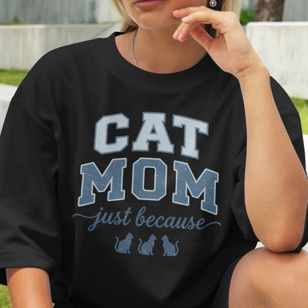 Person wearing a black t-shirt with 'CAT MOM just because' text and cat illustrations.