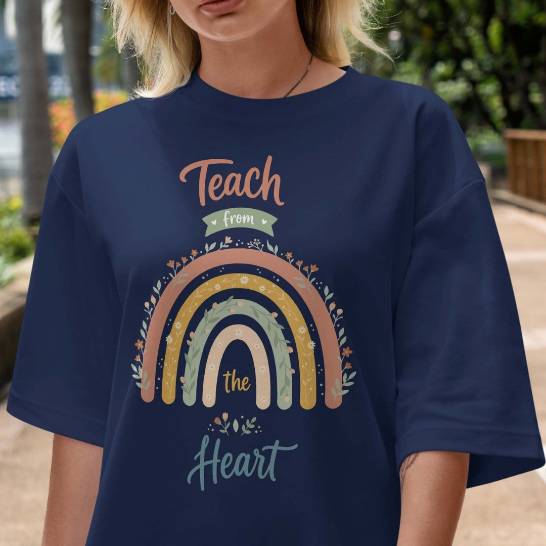 Person wearing a navy blue t-shirt with a rainbow design and text outdoors.