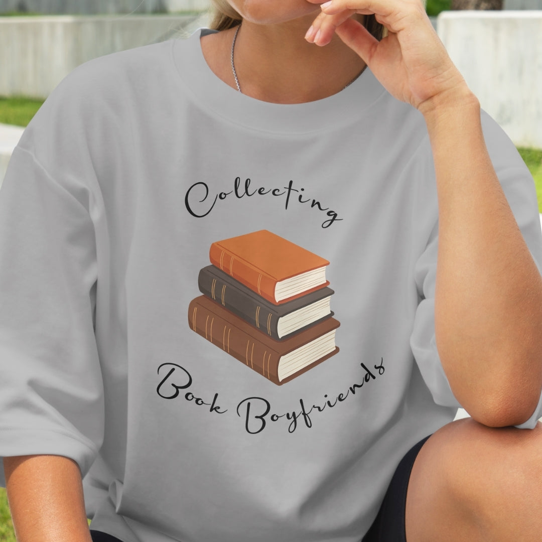 Person wearing a gray t-shirt with a graphic of books and text 'Collecting Book Boyfriends'.