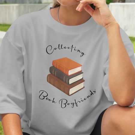 Person wearing a gray t-shirt with a graphic of books and text 'Collecting Book Boyfriends'.