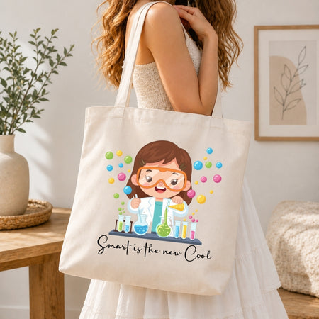 Person holding a tote bag with a cartoon scientist design and text 'Smart is the new Cool' in a home setting.