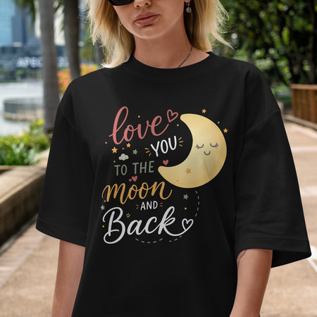 Person wearing a black t-shirt with a moon and text design outdoors.