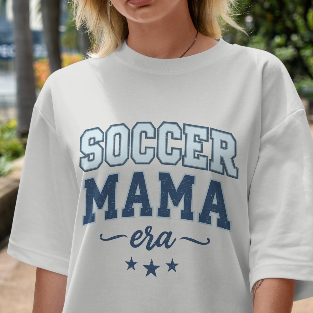 Person wearing a white t-shirt with 'Soccer Mama era' text in blue.