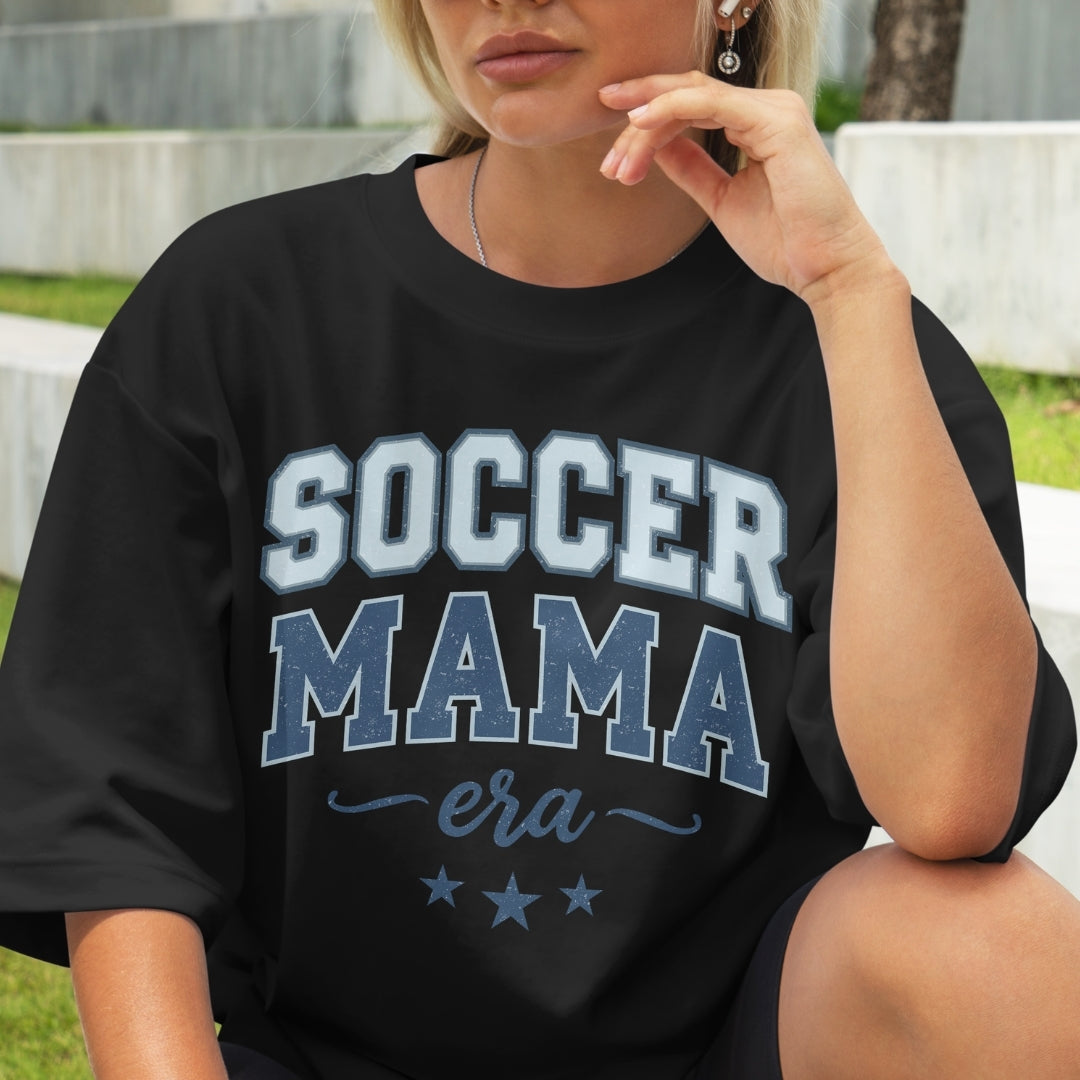 Person wearing a black t-shirt with 'Soccer Mama era' text.