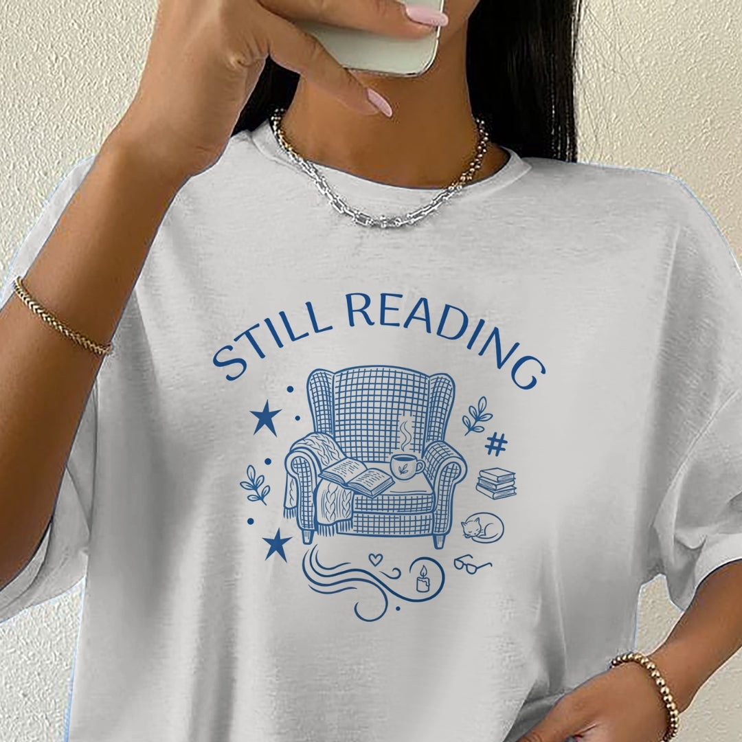 Person wearing a white t-shirt with 'STILL READING' graphic design.