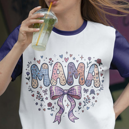 Person wearing a 'MAMA' shirt with decorative elements, holding a drink.