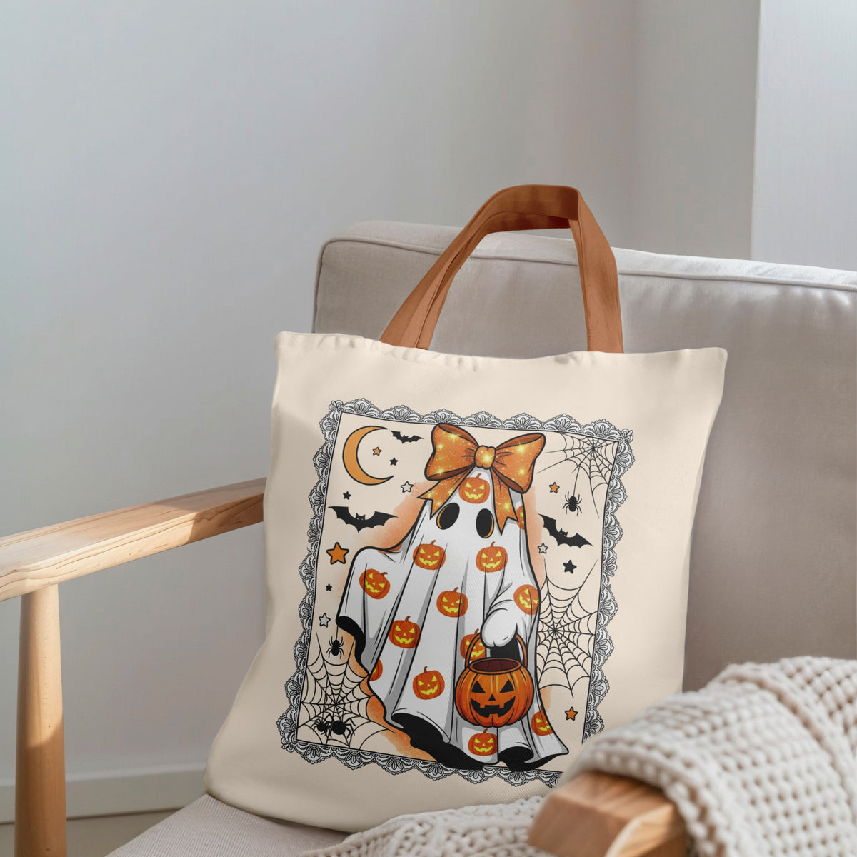 Tote bag with Halloween design featuring a ghost, pumpkins, and bats on a beige background.