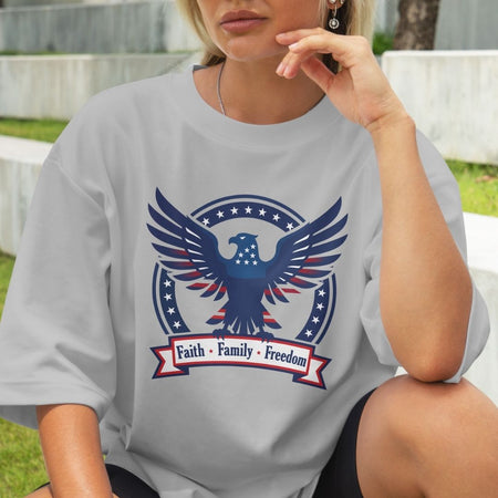 Person wearing a gray t-shirt with an eagle graphic and 'Faith Family Freedom' text.