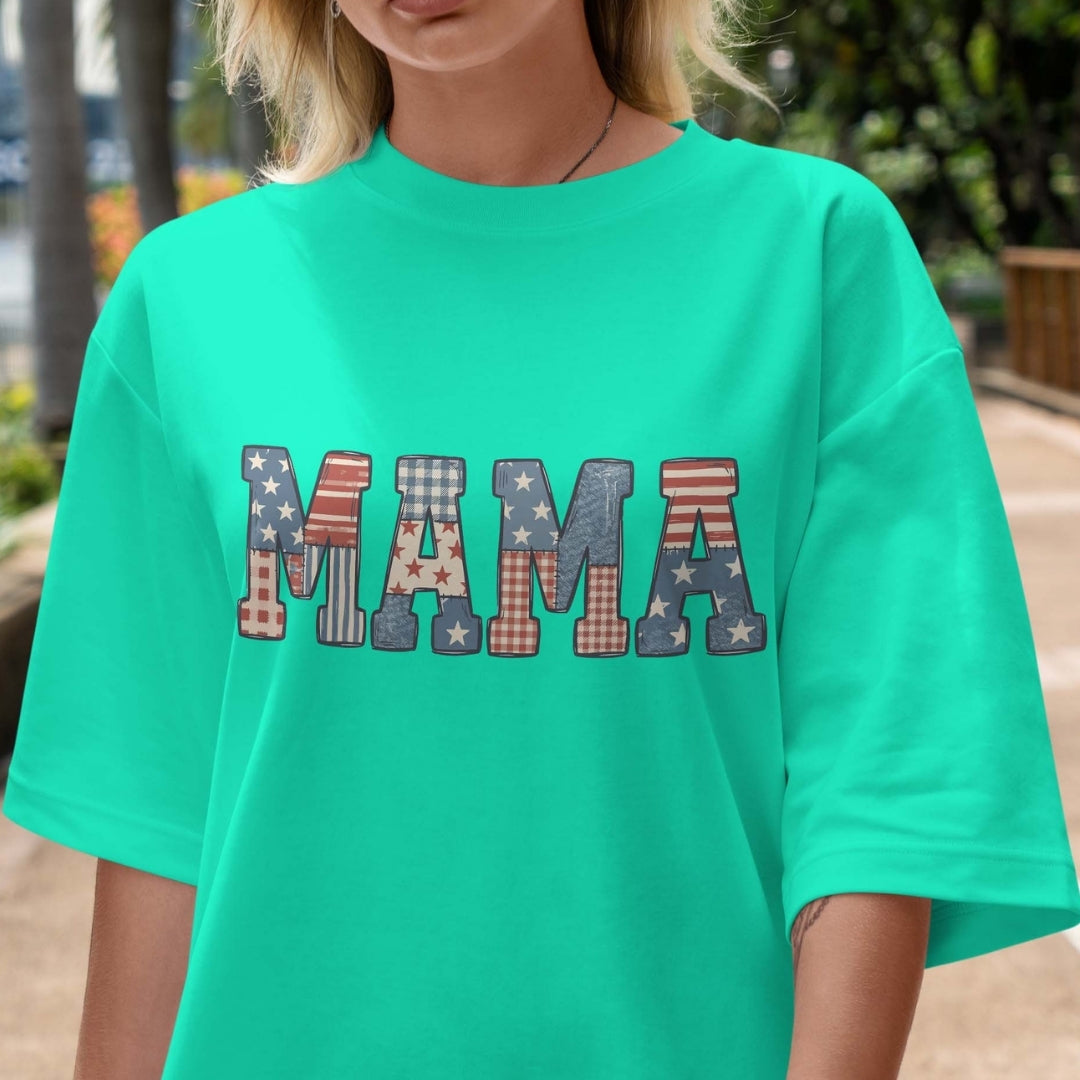 Person wearing a teal t-shirt with 'MAMA' printed in colorful letters.