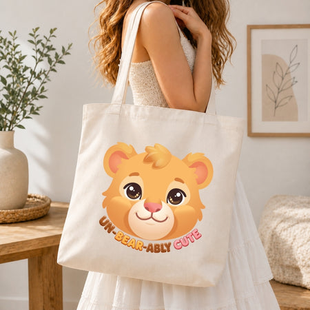 Person holding a tote bag with a bear face design and text in a home setting