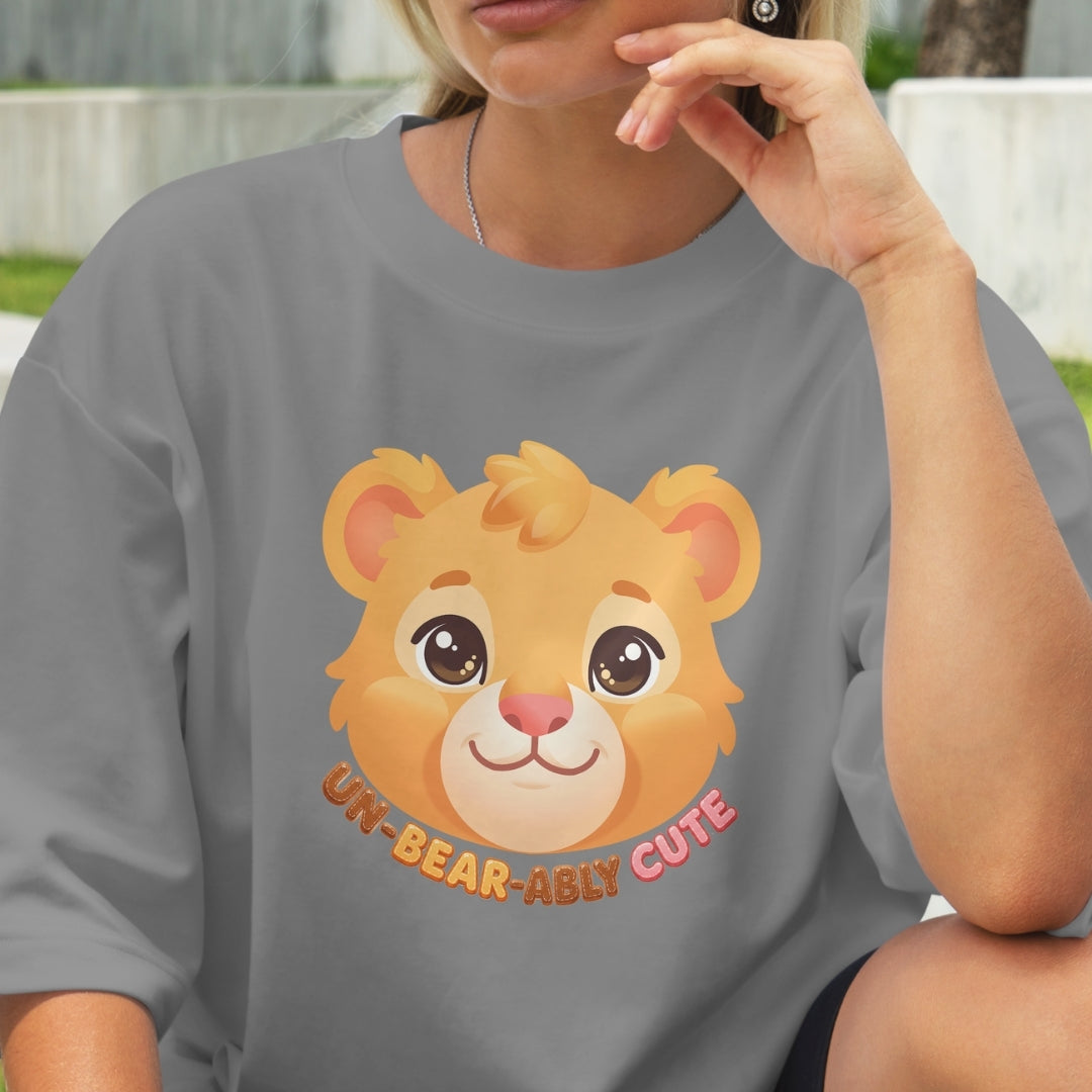 Person wearing a gray t-shirt with a cartoon lion and text 'UN-BEAR-ABLY CUTE'.