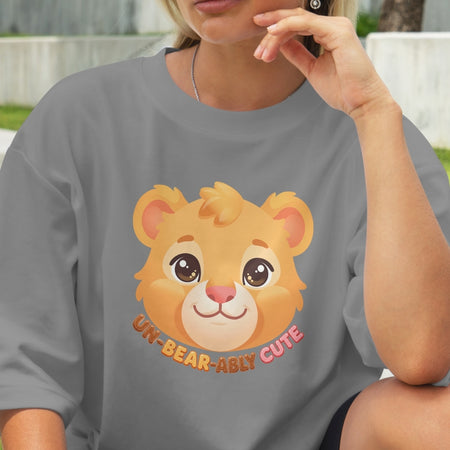 Person wearing a gray t-shirt with a cartoon lion and text 'UN-BEAR-ABLY CUTE'.
