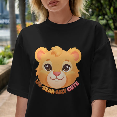 Person wearing a black t-shirt with a cartoon bear face and text outdoors.