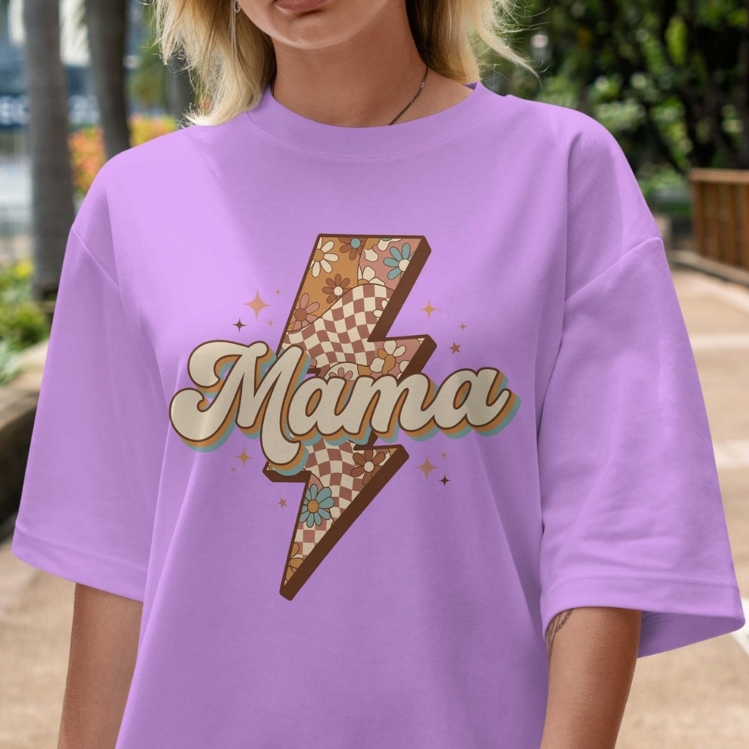 Person wearing a purple t-shirt with a 'Mama' graphic design outdoors.
