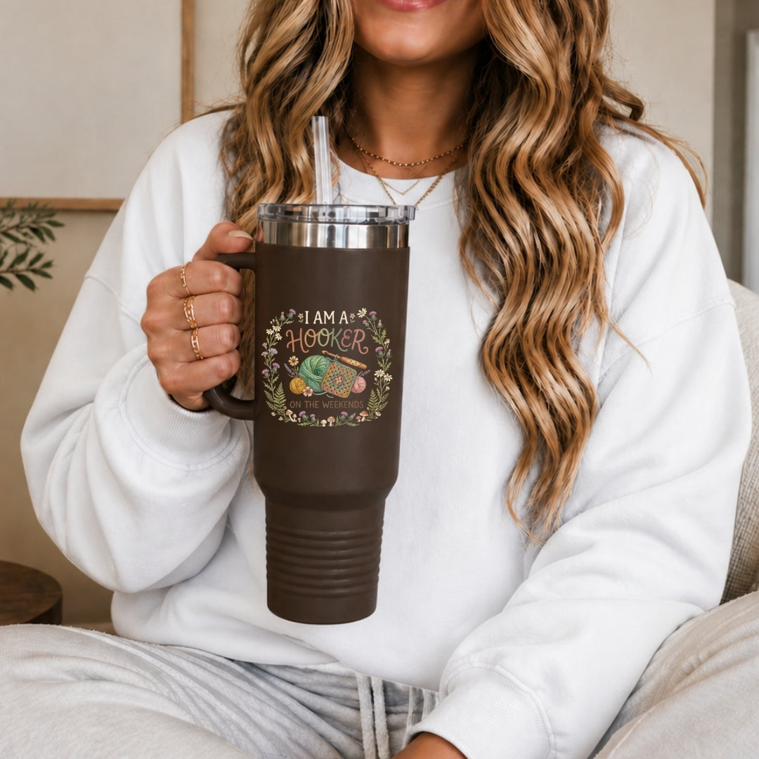 Person holding a brown insulated mug with a design and text, wearing a white sweatshirt.