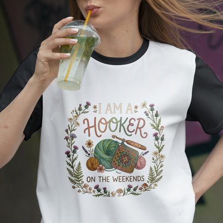 Person wearing a t-shirt with 'I am a hooker on the weekends' design, holding a drink.
